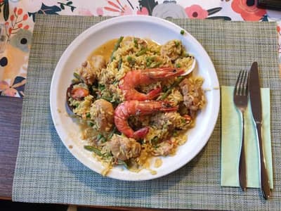 Teller mit frisch zubereiteter Paella mit Crevetten und Muscheln im Huefyse