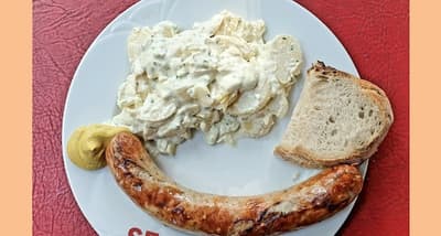 Teller mit Bratwurst, Kartoffelsalat, Senf und Brot im Huefyse, der Quartierbeiz im Basler Iselin