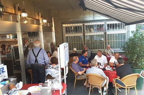 Gäste sitzen an Sommertischen auf der Terrasse vor dem Huefyse im Iselin, Basel